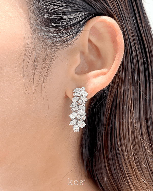 ต่างหูเพชรระย้าดีไซน์ช่อเพชรจาก Kos ประกอบด้วยเพชรทรงหยดน้ำและทรงกลมหลายเม็ดบนตัวเรือนสีขาว สำหรับใส่ออกงานหรู