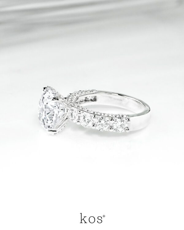แหวนหมั้นเพชร Starlight Pave & Side-Stone จาก Kos Jewelry, ภาพแหวนหมั้นหรูหราทรงบ่าไขว้ประดับเพชรเม็ดเดี่ยวและเพชร Pave