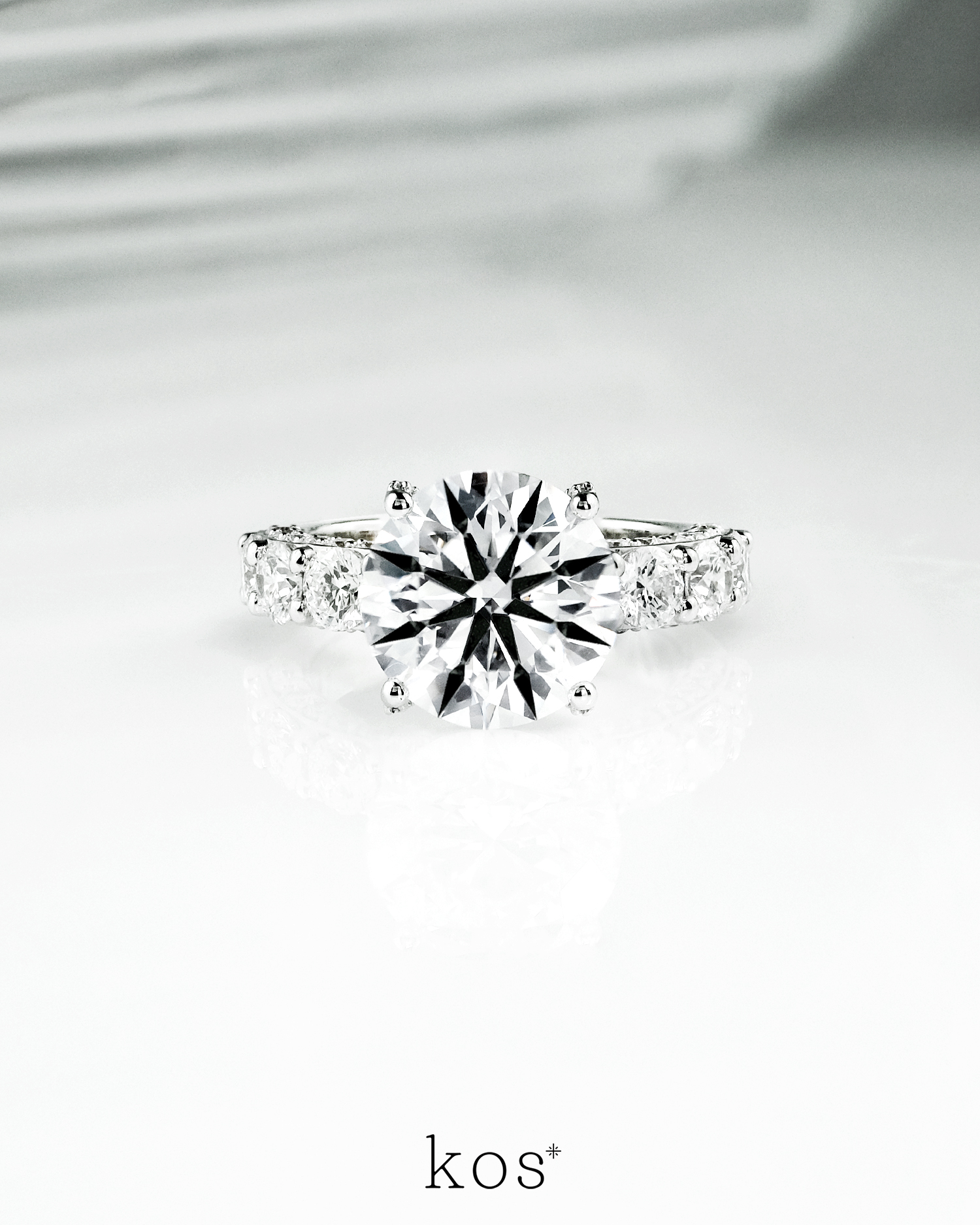 แหวนหมั้นเพชร Starlight Pave & Side-Stone จาก Kos Jewelry, ภาพแหวนหมั้นหรูหราทรงบ่าไขว้ประดับเพชรเม็ดเดี่ยวและเพชร Pave