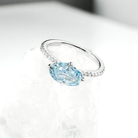 แหวนหมั้นเพชร Oval สีฟ้าทรง วางแนวนอน (East-West) บนตัวเรือนทองคำขาวฝังเพชร ดีไซน์แบรนด์ kos