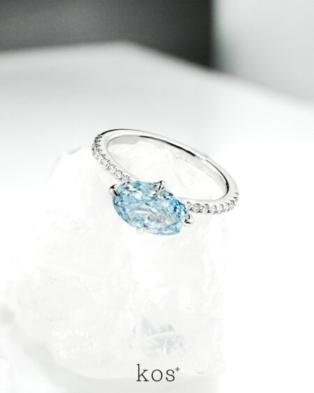 แหวนหมั้นเพชร Oval สีฟ้าทรง วางแนวนอน (East-West) บนตัวเรือนทองคำขาวฝังเพชร ดีไซน์แบรนด์ kos