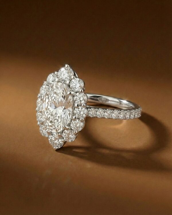 แหวนหมั้นเพชรทรงโอวัลล้อมเพชร ตัวเรือนทองคำขาวประดับเพชรที่ก้านแหวน